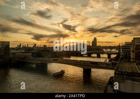 Fine della giornata lavorativa e pendolari a piedi oltre il Ponte di Londra come il sole tramonta Foto Stock