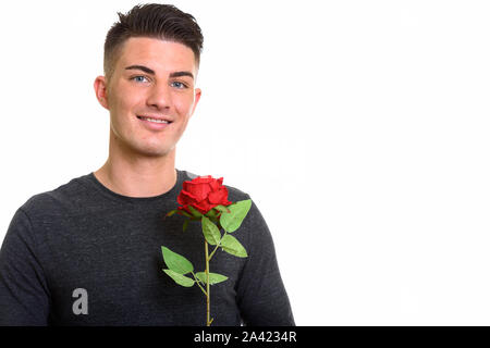 Studio shot di felice bel uomo sorridente mentre si tiene una rosa rossa Foto Stock