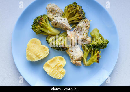 Cavolfiore con pezzi di carne. a forma di cuore di patate. su una piastra di blu. Pesce alla griglia. Pesce salmone bistecca con verdi, broccoli, cavolfiori Foto Stock