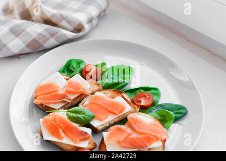 Panini con pesce rosso su una piastra bianca. decorate in verde Foto Stock