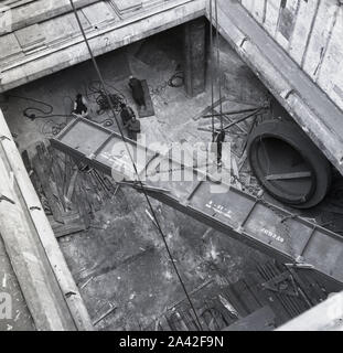 1950, storico, merci pesanti, una vista dall'alto di una grande sezione di acciaio, forse una parte di un ponte, che viene sollevata dallo scafo di una nave nel porto di Bombay (Mumbai), in India. Foto Stock