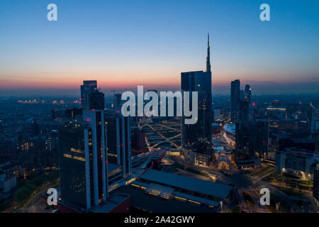 Antenna vista notturna di Milano prima di sunrise. Volando sopra la costruzione e il boulevard. Foto Stock