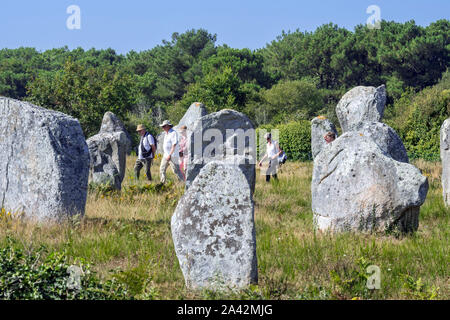 Guida con anziani turisti passeggiate tra gli allineamenti Ménec, sito megalitico tra il Carnac pietre permanente, Morbihan, in Bretagna, Francia Foto Stock