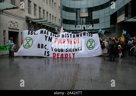 Manifestanti ambientali tenere un grande striscione bloccando l'accesso alla BBC edificio durante la dimostrazione.estinzione ribellione attivisti ambientali raccolte al di fuori della BBC a Londra per aumentare la consapevolezza dell'ecologica e crisi climatica e di esigere la copertura effettiva del crisi ambientale. Foto Stock