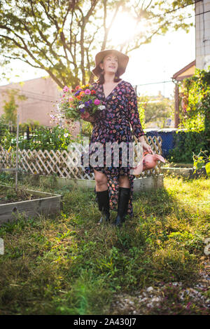 Donna felice in giardino urbano con fiori freschi Foto Stock
