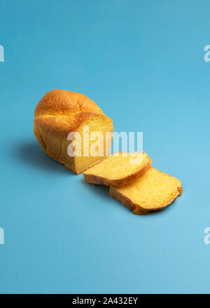 Gustosa cornbread, pane appena sfornato, con due fette su sfondo blu. Pane fatto in casa con la golden farina di mais. Europeo il pane di mais. Salutare il pane di mais. Foto Stock