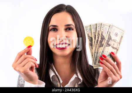 Virtual cryptocurrency denaro Bitcoin medaglia d'oro e dollari USA nelle mani di una donna con il rosso smalto per unghie. Bellissimo modello femminile sorridente. Il futu Foto Stock