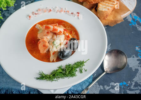 La dieta di zuppa di pesce e frutti di mare e pesci di diverse varietà in una piastra bianca. Close up. Foto Stock