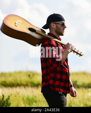 Trasognata wanderer. Atmosfera pacifica. Escursionismo canzone. Un musicista in cerca di ispirazione. Uniti con la natura. Ispirando la natura. Uomo bello con la chitarra a contemplare la natura. In cerca di muse. La vacanza estiva. Foto Stock