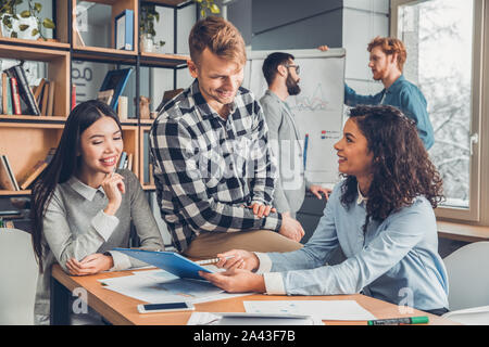 Startupers lavorando insieme a Office donna seduta al tavolo per discutere di un progetto con guy gioiosa Foto Stock
