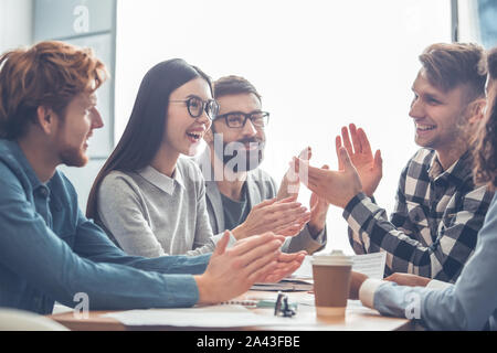 Startupers lavorando insieme in ufficio di affari battimani ot ogni altra gioiosa Foto Stock
