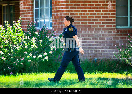 Poliziotta attraversando a piedi una casa cortile anteriore durante un tempo tesa durante un incidente in Tucson AZ Foto Stock