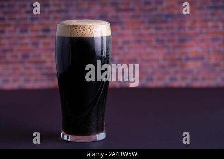 Una scura Guinness Irish Stout secca bicchiere di birra che ha origine nella fabbrica di birra a Dublino vista orizzontale Foto Stock