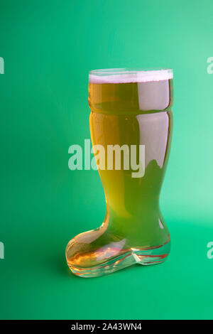 La birra nel bagagliaio di un bicchiere di birra in sfondo verde Foto Stock