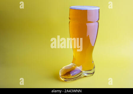 La birra nel bagagliaio di un bicchiere di birra in sfondo giallo Foto Stock