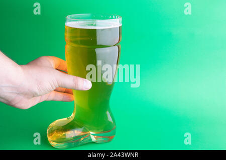 Una mano che tiene una birra in vetro di avvio in sfondo verde Foto Stock