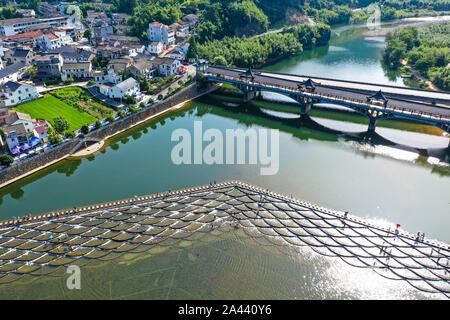 I visitatori un tuffo per rinfrescarsi in acqua in una posizione nota per il pesce in scala barriere sagomati che formano piccole cascate nel quartiere Fuyang, Hangzhou ci Foto Stock
