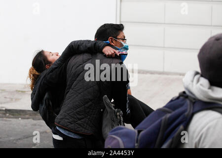 Quito, Ecuador. Undicesimo oct, 2019. Un dimostratore sta portando a una donna malata. Venerdì ci sono stati gravi scontri con la polizia in nuove manifestazioni di protesta contro l'aumento dei prezzi del carburante in Ecuador. Credito: Sara Bandes/dpa/Alamy Live News Foto Stock