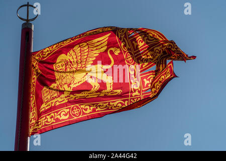 Venezia bandiera rossa con golden lion sventolare nel cielo blu sullo sfondo Foto Stock