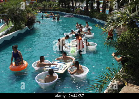 I residenti locali gioca mahjong e godere di un gigante di ghiaccio-ventosa su una torrida giornata presso una piscina a Chongqing Cina, 13 agosto 2019. Foto Stock