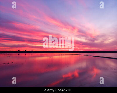 Vista aerea del drone shot sulla superficie di acqua in Twilight, ora d'oro del tramonto. Vista stupefacente, firth superficie riflettente majestic rosso e rosa nuvole. Foto Stock