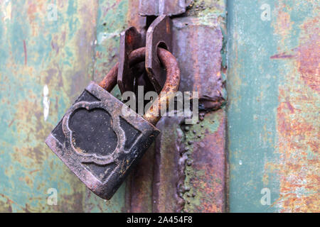 Vecchie e arrugginite lucchetto con graffi blocca le porte in acciaio di una volta abbandonati Foto Stock