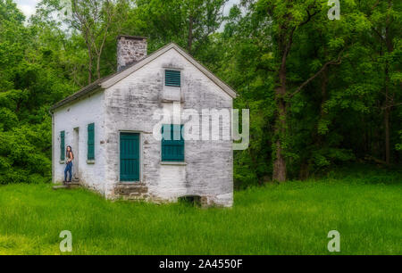 Donna in piedi da bloccare i detentori casa bianca con persiane verdi e porta a Chesapeake e Ohio Canal Foto Stock