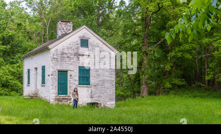 Donna in piedi da bloccare i detentori casa bianca con persiane verdi e porta a Chesapeake e Ohio Canal Foto Stock