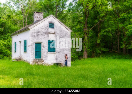 Donna in piedi da bloccare i detentori casa bianca con persiane verdi e porta a Chesapeake e Ohio Canal Foto Stock