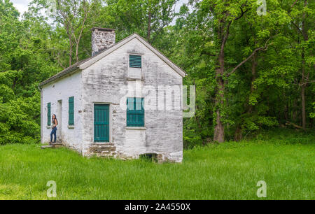 Donna in piedi da bloccare i detentori casa bianca con persiane verdi e porta a Chesapeake e Ohio Canal Foto Stock