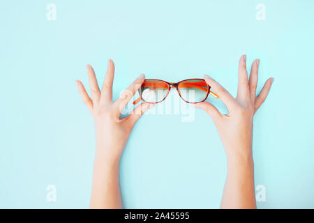 Mani femminili tenendo delicatamente i bicchieri sul corallo sbiancato sfondo. Foto Stock