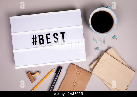 Hashtag con la parola migliore. Lightbox bianco su grigio di una scrivania in ufficio. Il social media marketing e motivazione Foto Stock