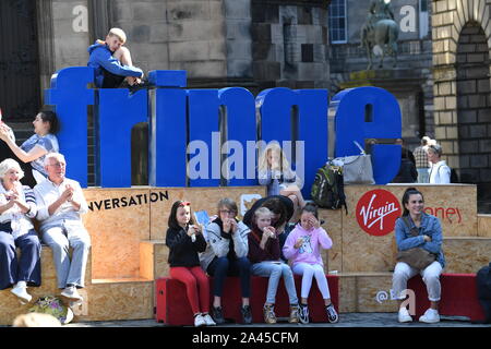 2019 Edinburgh Fringe - i giovani spettatori di prendere un periodo di riposo durante le esibizioni in strada sul Royal Mile. Foto Stock