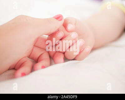 Mano materna tiene il suo bambino. I bambini neonati la mano nella mano madre. La mamma e il suo bambino. Happy Family concept. Bella immagine concettuale della maternità Foto Stock