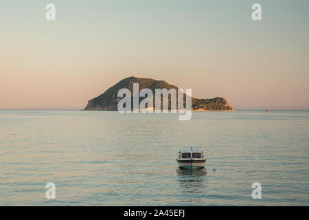 Vista dal mare di Marathonisi o Turtle Island vicino isola greca di Zante nel Mar Ionio wuht una barca di fronte ad esso. Foto Stock