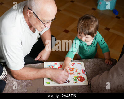 Un ragazzo sta giocando con il nonno. Nonno e nipote si diverte. giocato un artigianale di gioco di bordo con il nonno. Foto Stock