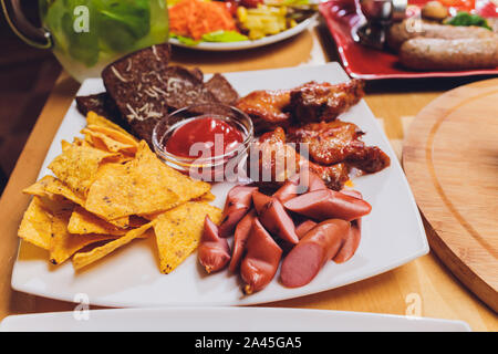 Pasti sani servita a tavola festiva servita per party. Amici festeggiare con cibo organico su un tavolo di legno vista dall'alto. Gli uomini e le donne passano piatti per AEC Foto Stock