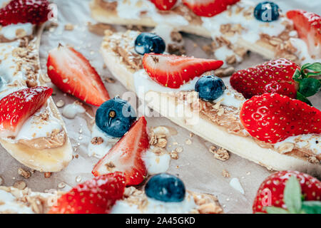 Banana Split con fragole, mirtilli, burro di mandorla e miele Foto Stock