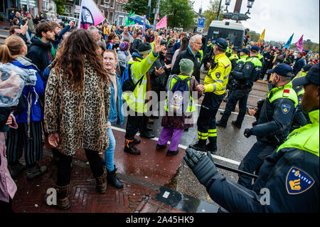 Amsterdam, Paesi Bassi. Xii oct, 2019. I manifestanti bloccati da poliziotti durante la dimostrazione.centinaia di estinzione della ribellione attivisti bloccato uno dei ponti importanti in Amsterdam, il Blauwbrug nel centro della città in modo che il governo olandese è in grado di riconoscere la crisi climatica. Credito: SOPA Immagini limitata/Alamy Live News Foto Stock