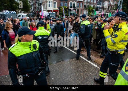 Amsterdam, Paesi Bassi. Xii oct, 2019. Poliziotti di stare in guardia durante la dimostrazione.centinaia di estinzione della ribellione attivisti bloccato uno dei ponti importanti in Amsterdam, il Blauwbrug nel centro della città in modo che il governo olandese è in grado di riconoscere la crisi climatica. Credito: SOPA Immagini limitata/Alamy Live News Foto Stock