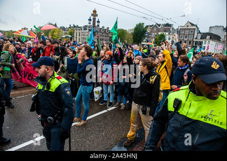 Amsterdam, Paesi Bassi. Xii oct, 2019. I manifestanti bloccati da poliziotti durante la dimostrazione.centinaia di estinzione della ribellione attivisti bloccato uno dei ponti importanti in Amsterdam, il Blauwbrug nel centro della città in modo che il governo olandese è in grado di riconoscere la crisi climatica. Credito: SOPA Immagini limitata/Alamy Live News Foto Stock