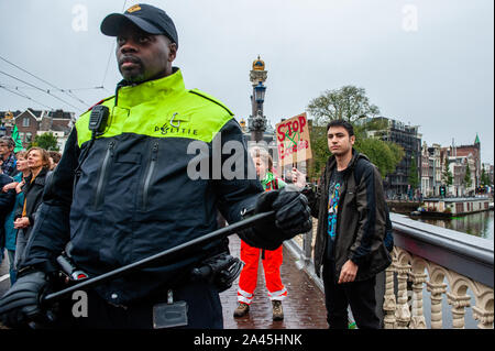 Amsterdam, Paesi Bassi. Xii oct, 2019. Un poliziotto si affaccia su durante la dimostrazione.centinaia di estinzione della ribellione attivisti bloccato uno dei ponti importanti in Amsterdam, il Blauwbrug nel centro della città in modo che il governo olandese è in grado di riconoscere la crisi climatica. Credito: SOPA Immagini limitata/Alamy Live News Foto Stock