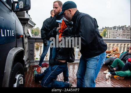 Amsterdam, Paesi Bassi. Xii oct, 2019. Poliziotti di cattura di un manifestante durante la dimostrazione.centinaia di estinzione della ribellione attivisti bloccato uno dei ponti importanti in Amsterdam, il Blauwbrug nel centro della città in modo che il governo olandese è in grado di riconoscere la crisi climatica. Credito: SOPA Immagini limitata/Alamy Live News Foto Stock