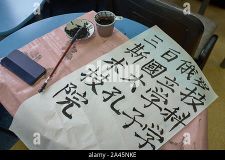 Inchiostro Cinese pennello e gocce di inchiostro in lavoro. Dopo la scrittura di alcuni caratteri cinesi su un foglio di carta. Foto Stock