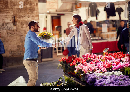 Donna felice shopping per le piante al negozio di fiori sulla strada. Foto Stock