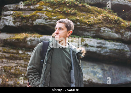 Ritratto di giovane uomo in kaki parka giacca con zaino, viaggi avventura lifestyle Foto Stock