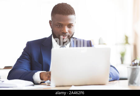 Concentrate i giovani proprietari che lavorano in ufficio con computer portatile Foto Stock