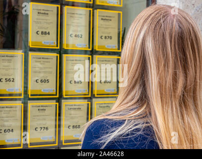 Donna guarda per offerte di viaggio Foto Stock