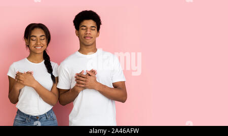 Concetto di riconoscenza. Tipo ragazzo e ragazza mantenendo le palme sul petto Foto Stock