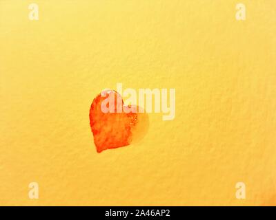 Rosso piccolo cuore bagnato dipinta su carta gialla. Spazio di copia Foto Stock